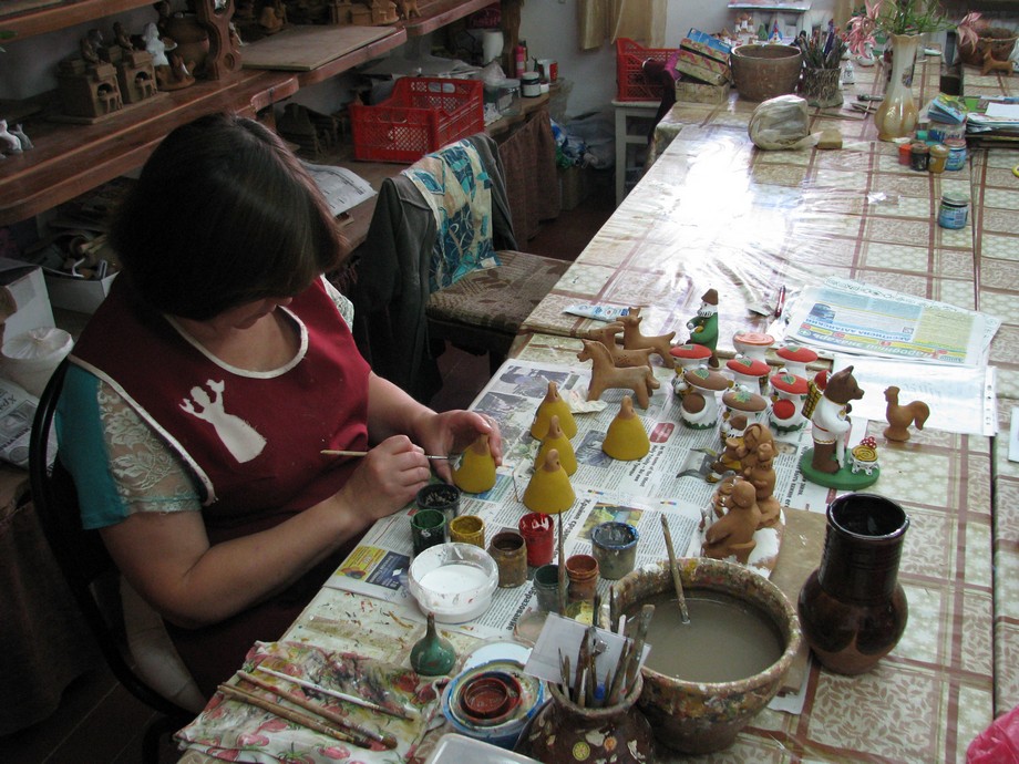 Мастер за росписью глиняных игрушек. В каргопольской традиции нет разделения труда: один мастер и лепит, и расписывает игрушку